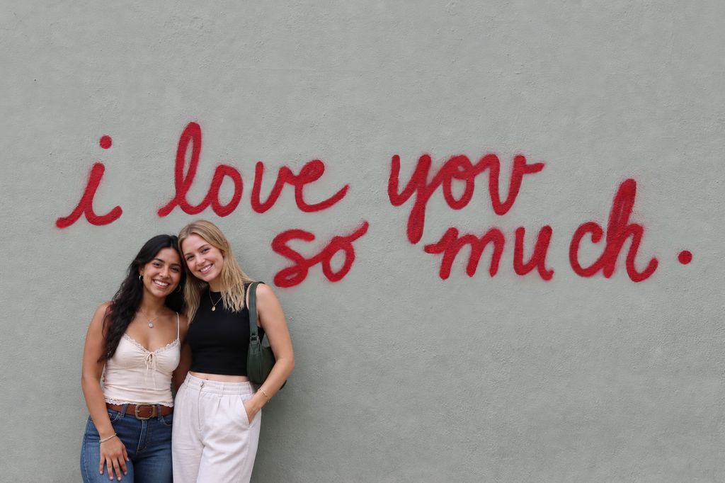 Two friends posing together at a mural